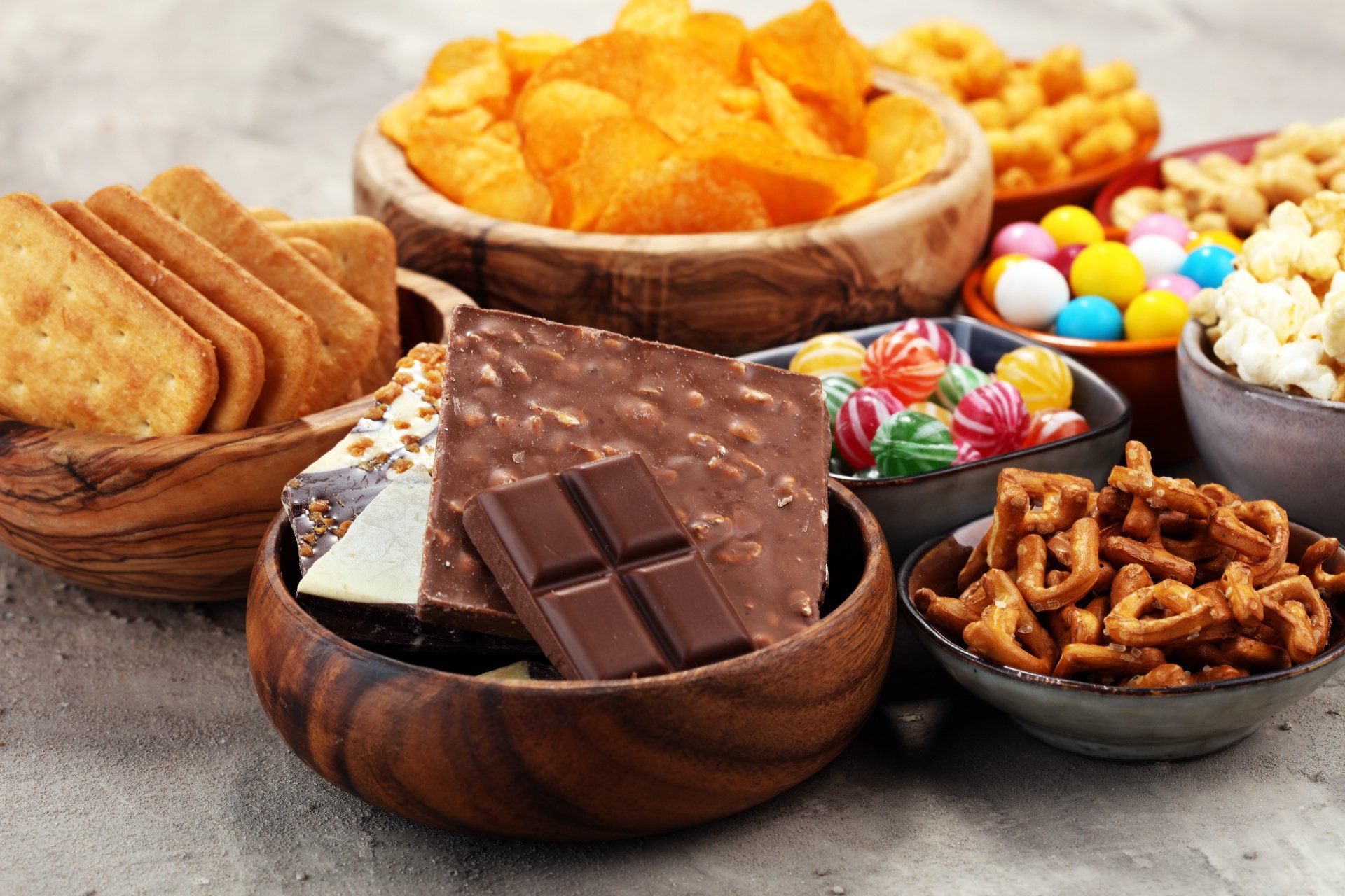Selection of snacks: bowl of chocolate, bowl of hard boiled sweets, bowl of crisps or corn chips