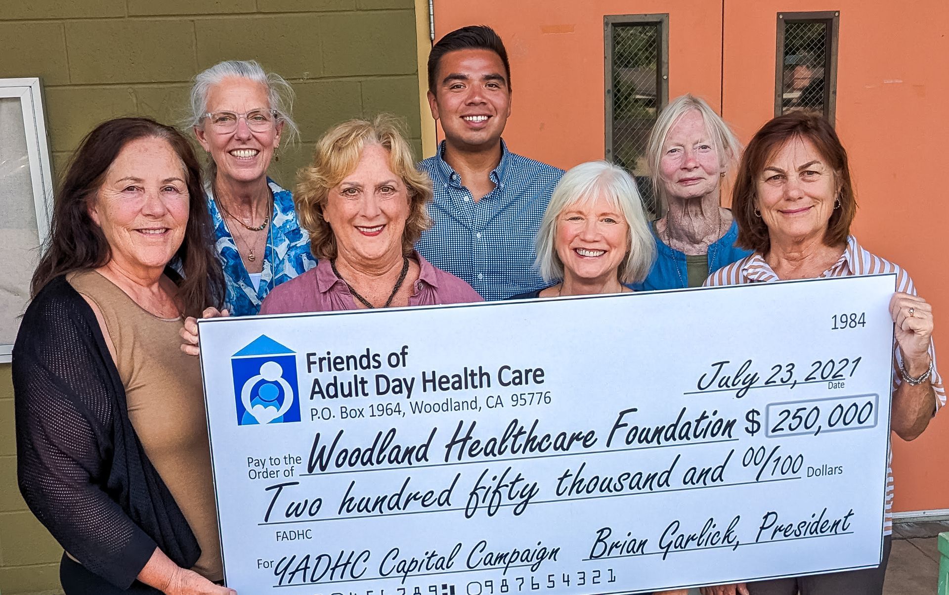 Group holding a large check for the Friends of Adult Day Health Care fundraiser indoors