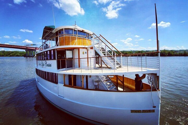 A large white boat is floating on top of the hudson river
