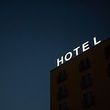 A hotel sign is lit up at night on the roof of a building.