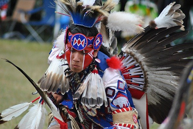 A man in a native american costume is dancing on the Wind River Indian Reservation