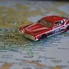 A red toy car is sitting on top of a map.
