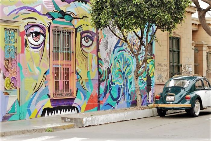 A car is parked in front of a wall with graffiti on it in Lima