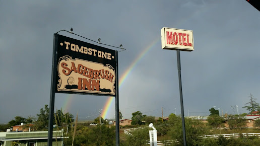 A motel sign in tombstone  with a rainbow in the background