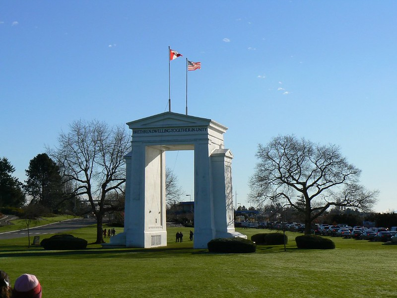 A white archway with two flags on top of it in peace arch park