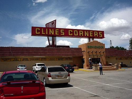 A red car is parked in front of a building that says clines corners