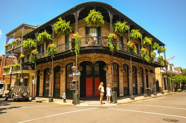 A couple of people are standing in front of an iconic building with balconies in new orleans.
