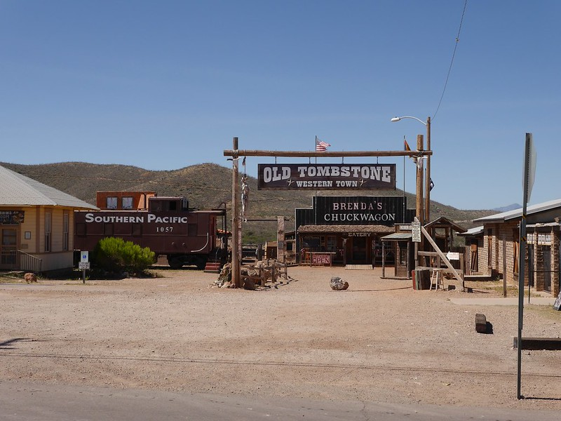 A train car is parked in front of a sign that says old tombstone