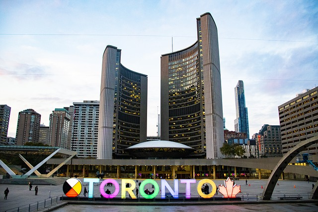 A sign that says Toronto in front of Toronto skyline.