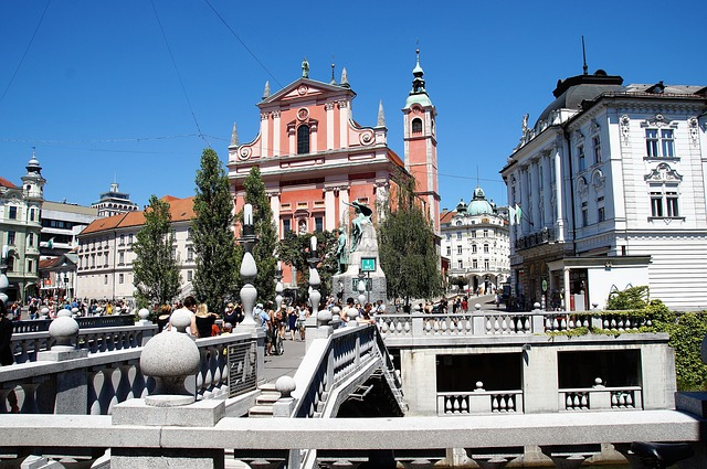A bridge over a river in Ljubljana with a church in the background