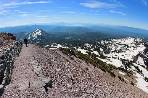 A person is walking down the lassen peak trail on top of a mountain.