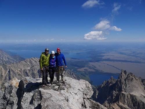 Three people are standing on top of a mountain in grand teton np