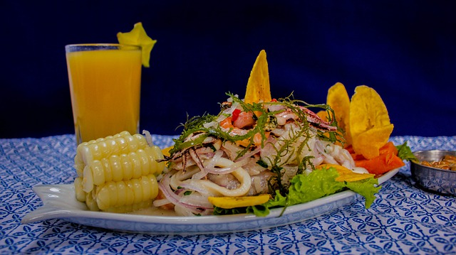 A plate of South American food with corn on the cob and a glass of orange juice on a table.