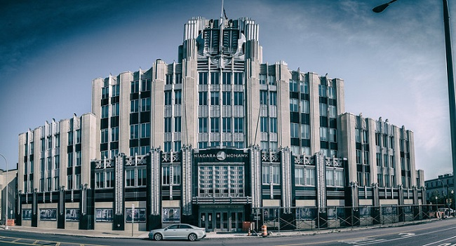 The Marriot Syracuse Downtown hotel with a lot of windows and a car parked in front of it.