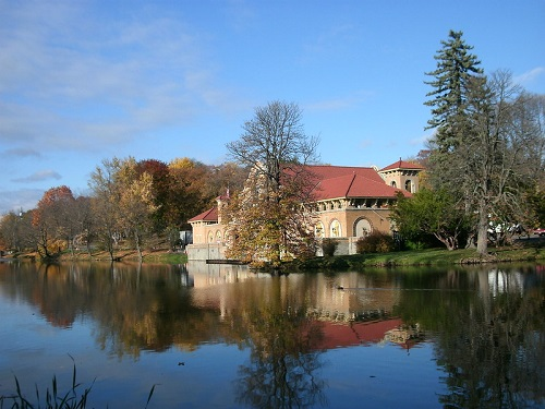 A house with a red roof sits on a small island in the middle of a lake in washingron park
