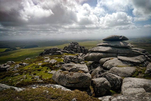 A stack of rocks on top of a hill on Bodmin Moor with a cloudy sky in the background.
