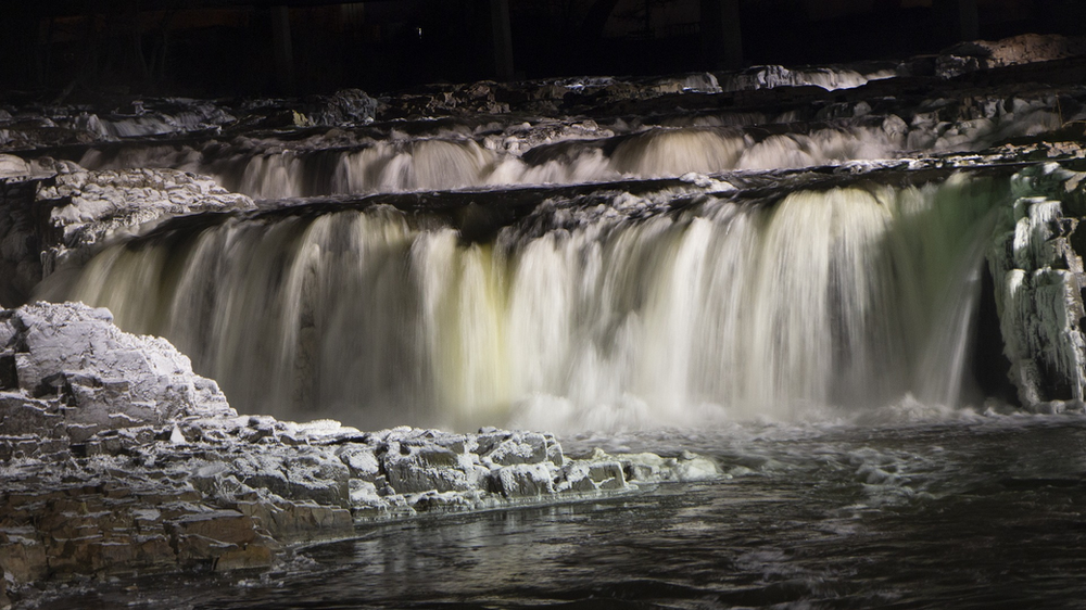 A waterfall in Sioux Falls is surrounded by rocks and trees