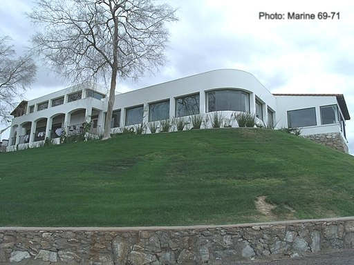 A large white house known as the wrigley mansion sits on top of a grassy hill