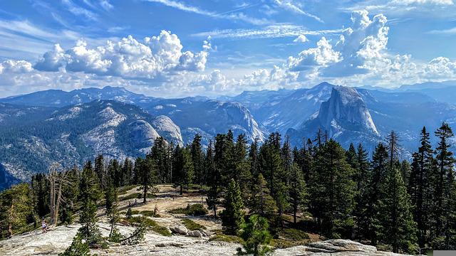 A view of a mountain range in yosemite np with trees in the foreground and mountains in the background.