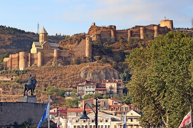 A statue of a man on a horse is in front of a castle on a hill in georgia