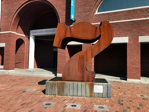 A large rusty sculpture in front of the portland museum of art