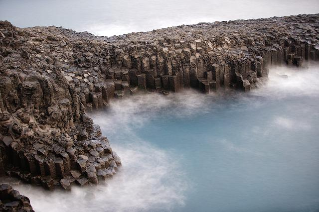 A long exposure photo of a rocky cliff overlooking a body of water in jeju