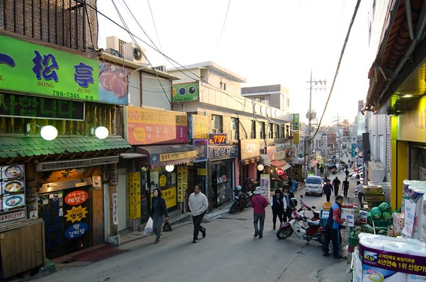 A group of people are walking down a busy street in Seoul