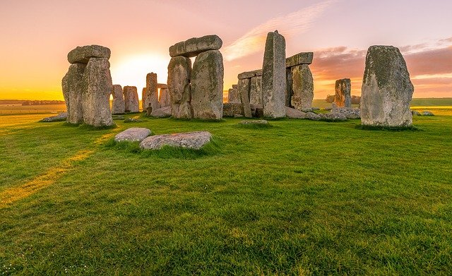 Stonehenge surrounded by grass and a sunset in the background.