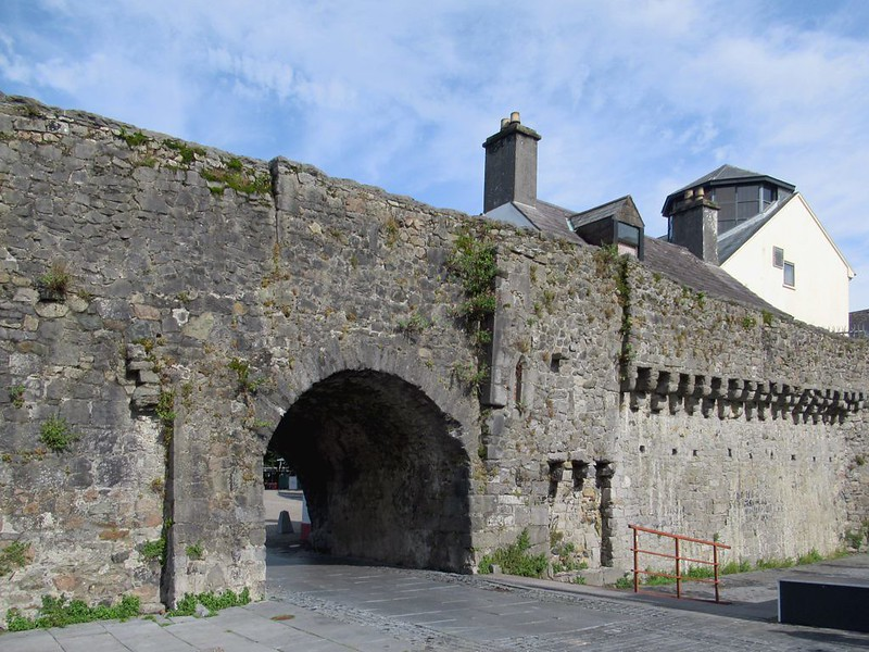 A stone wall with the famed Spanish Arch archway leading to a building