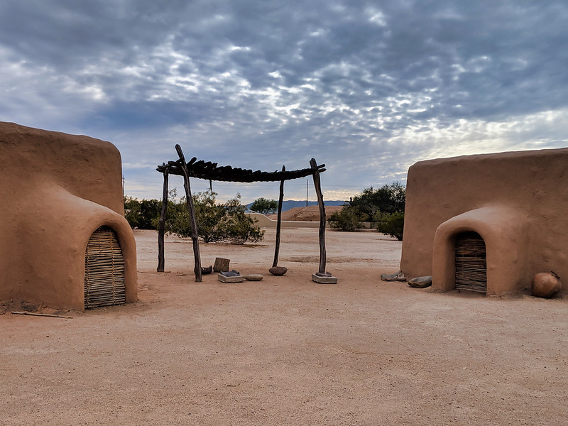 Two adobe buildings in Pueblo Grande Museum Archaeological Park with a pergola in the middle