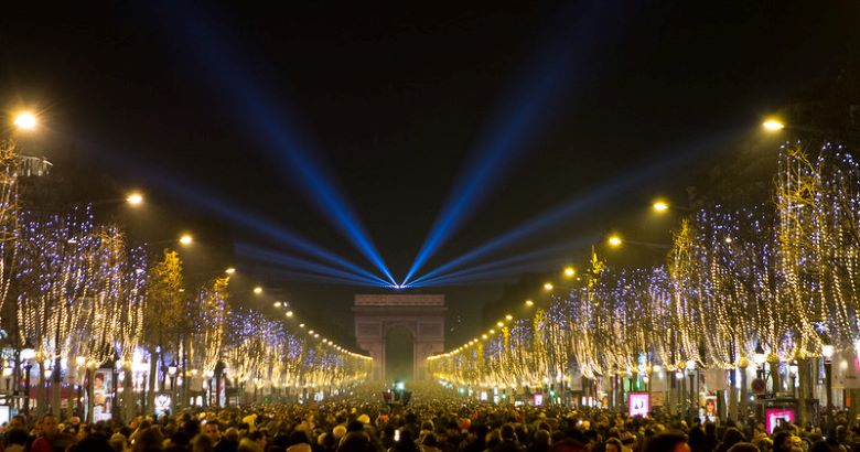 A crowd of people are gathered in a city street at night.