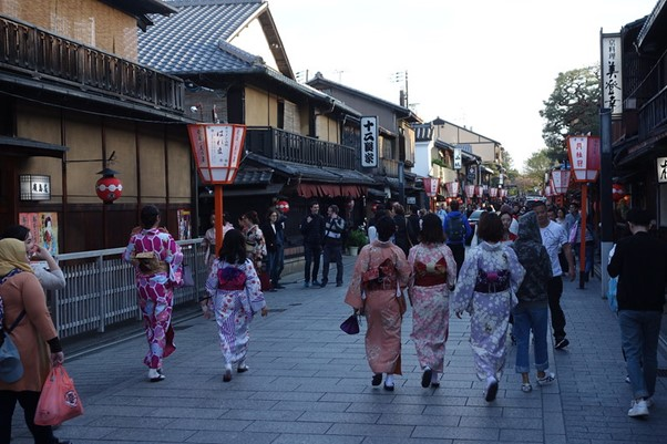 A group of people in kimonos are walking down a street in gion