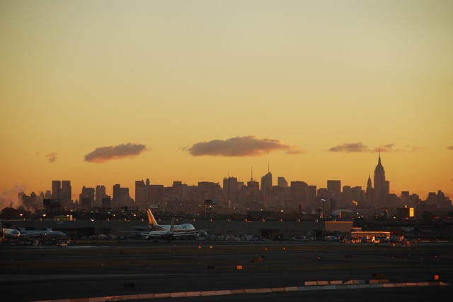 A sunset over the new york city skyline with a runway in the foreground.