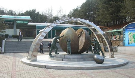 A group of people are standing around a large sculpture at the DMZ