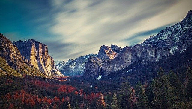 There is a waterfall in the middle of the mountains in yosemite national park.