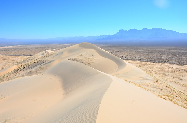 A sand dune in the middle of the Mojave National Preserve with mountains in the background.