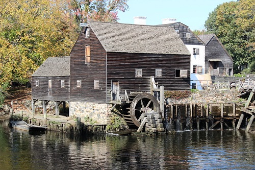 A large wooden building with a water wheel in front of it in Sleepy Hollow