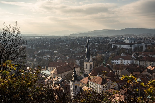 An aerial view of Ljubljana with a church and mountains in the background.