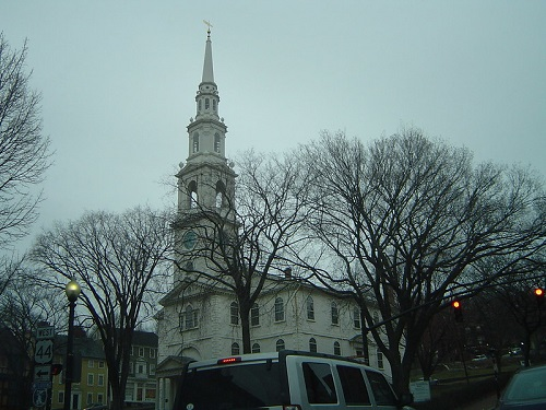A white van is parked in front of The First Baptist Church In America