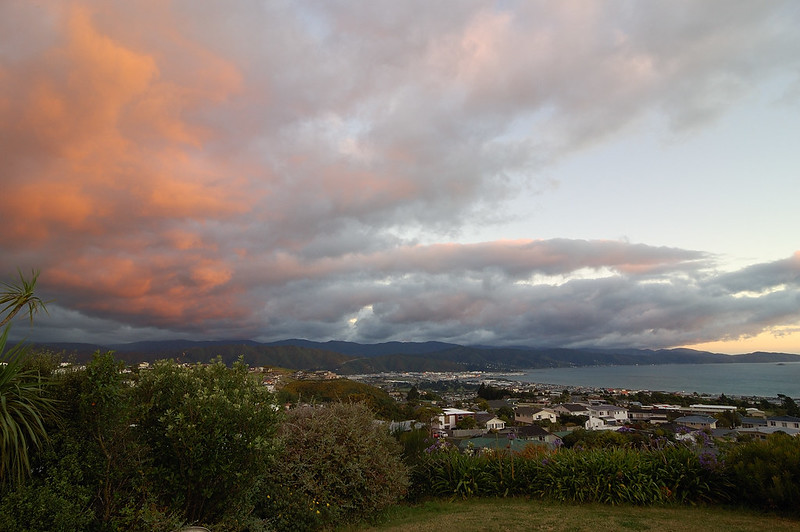 A sunset over Wellington with a cloudy sky and mountains in the background.
