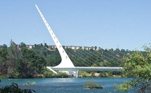 the sundial bridge over a body of water in redding with trees in the background