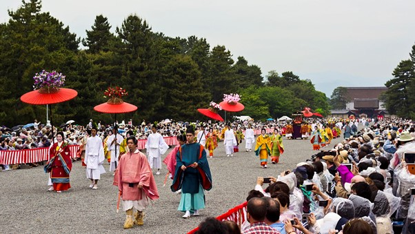 A crowd of people are watching a parade in the imperial palace and gardens