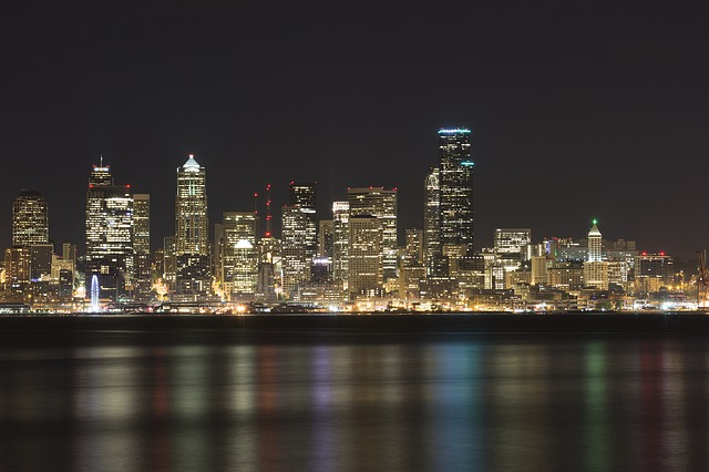 the seattle skyline at night with a body of water in the foreground.