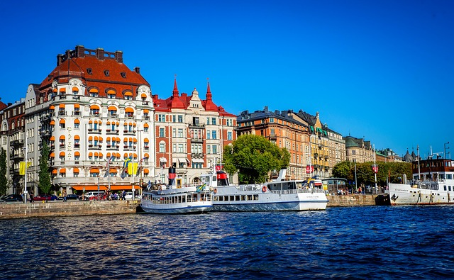 A boat is docked in front of a building next to a body of water in stockholm