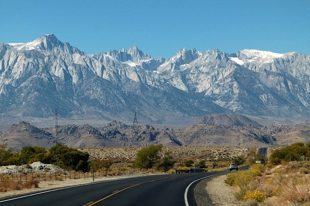 A road going through a desert in California with mountains in the background
