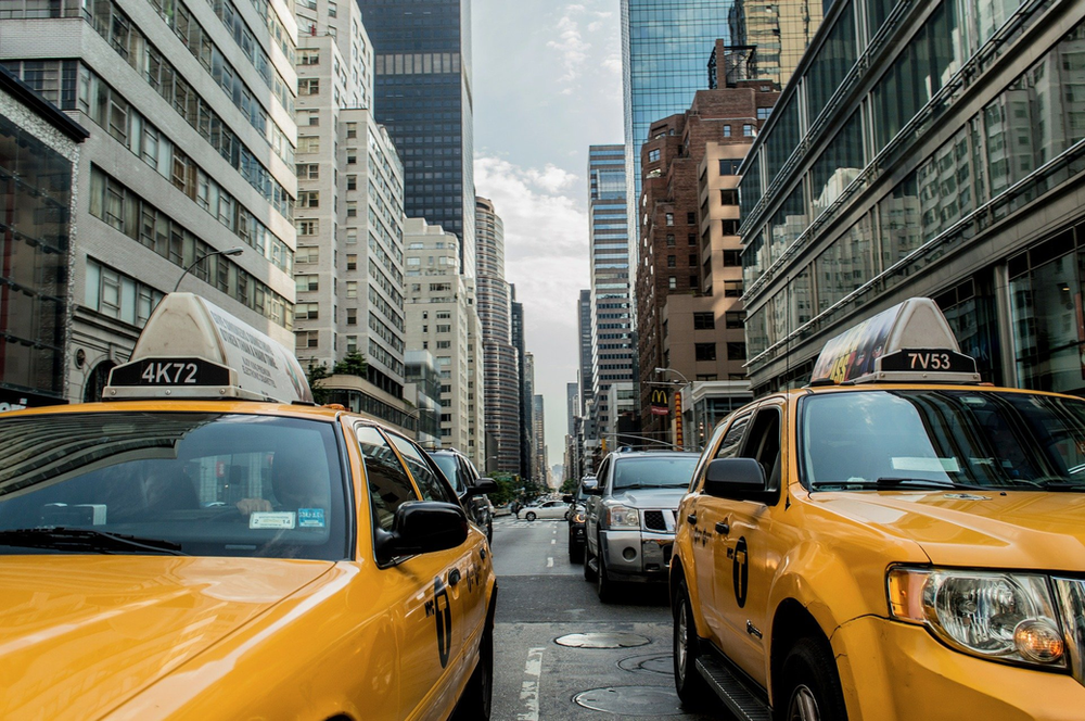 A row of yellow taxis are parked on the side of a new york city street.