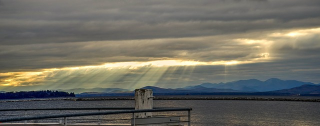 The sun is shining through the clouds over Lake Champlain