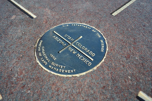 A plaque on the ground at Four Corners Monument that says utah colorado arizona new mexico