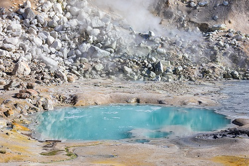 There is a small geothermal pool of water in the middle of a rocky area in lassen volcanic np