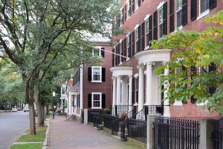 A row of brick houses with porches on the side of a street in salem